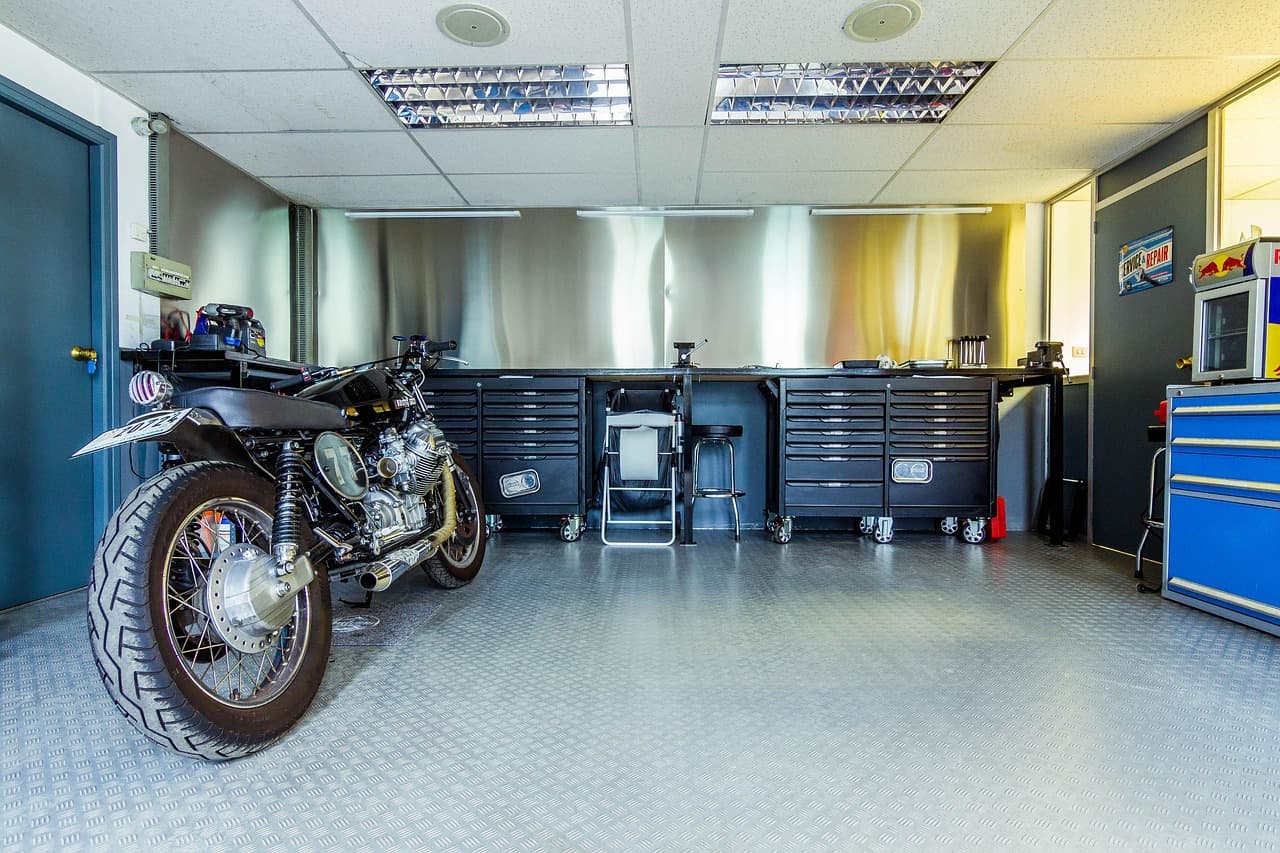 A motorcycle parked in a clean, well-lit workshop beside the tool chests