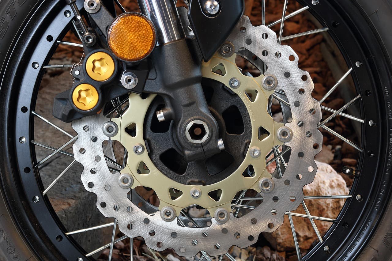 A motorcycle front wheel close up: spokes, brake disc and caliper