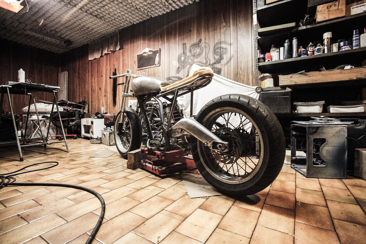 A motorcycle up on a stand in a workshop, ready to be worked on